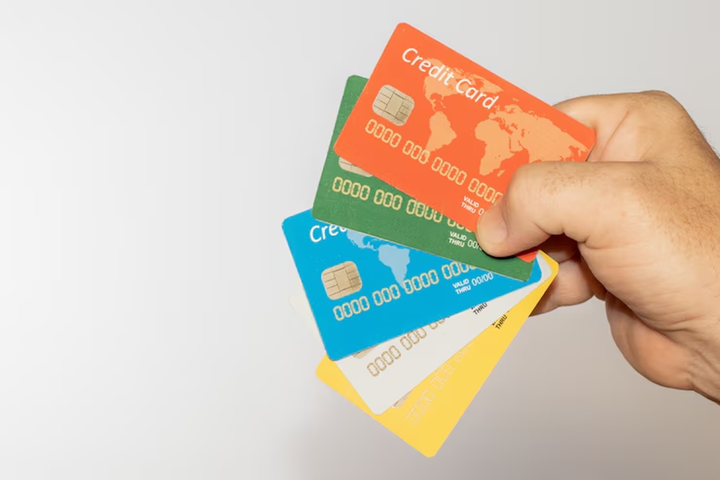 Mão masculina segura diversos cartões coloridos com design internacional, sugerindo múltiplas opções de uso global — uma representação visual do uso estratégico de cartão de crédito em dólar em compras e transações no exterior.