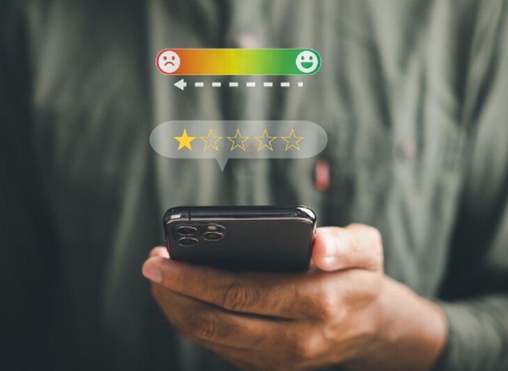 Pessoa segurando um smartphone enquanto avalia negativamente um serviço com apenas uma estrela, representando insatisfação comum em processos de solicitação de empréstimo pessoal com score baixo.