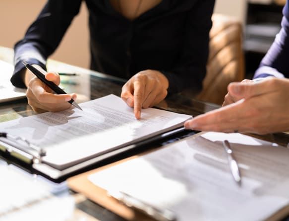 Duas pessoas analisando e assinando documentos em uma mesa de escritório, representando a formalização de um contrato de empréstimo pessoal.